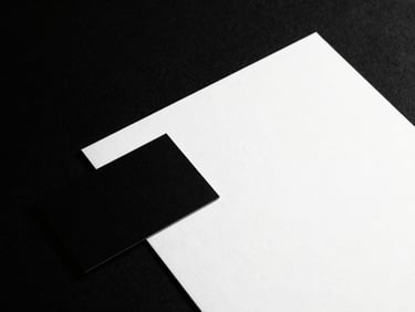High-contrast, stark black and white studio shot of a minimalist business card and letterhead, crisp shadows, 50mm lens, premium editorial lookbook