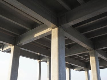 Crisp architectural photography of exposed structural steel columns and beams under dramatic morning daylight, sharp focus on bolted framing connections