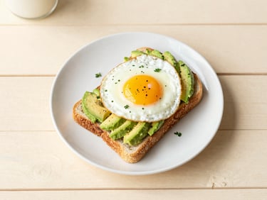 top-down flat lay of a vibrant breakfast plate with avocado toast and a perfectly fried egg, fresh herbs, on a sunlit wooden table, soft morning light, warm cream and pastel tones, shallow depth of field