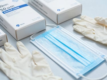 Close-up of sealed, clinical-grade medical consumables including boxes of nitrile gloves and surgical masks, sharp focus, sterile environment, 50mm