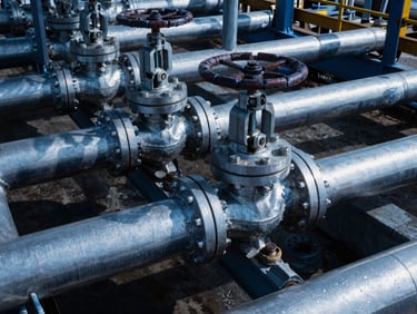 Close-up of industrial steel valves and pipelines at a deepwater oil terminal, cold steel-blue tones, sharp highlights, 35mm