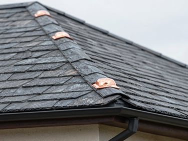 Close-up of slate roof shingles and copper flashing on a residential building, sharp focus, natural overcast lighting