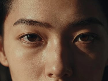 Extreme close-up of a high-fashion model's eyes in deep chiaroscuro lighting, dramatic shadows, warm muted gold tones, 35mm film grain