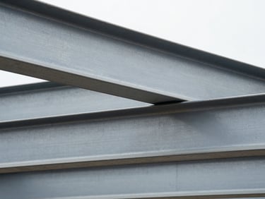 Close-up, abstract shot of stacked industrial steel beams, clean geometric lines, cool, desaturated metallic tones, sharp focus.