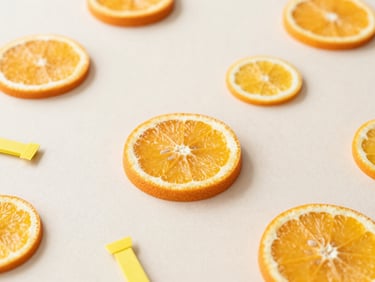 Flat-lay of a baby shower theme with citrus slices, orange and yellow decor, and small party favors, clean background.