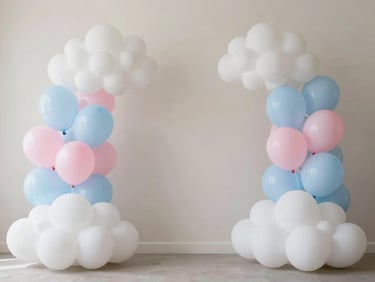 Stylized baby shower setup featuring fluffy cloud decorations, light blue and pink pastel balloons, and soft lighting.