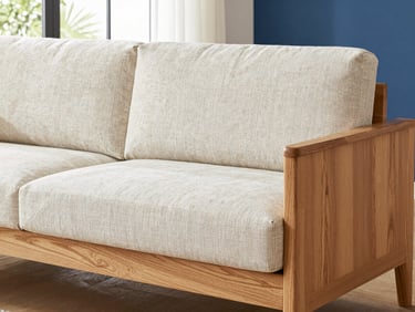Close-up detail of textured linen upholstery fabric being hand-stretched over a solid oak sofa frame, bright natural daylight, 35mm