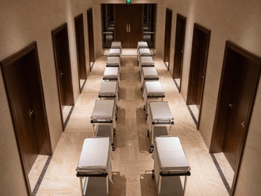Overhead wide view of a luxury hotel housekeeping operations corridor at night, rows of linen trolleys lined with precision under cold corridor lighting, no staff present, geometric symmetry of doors and carts