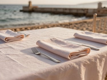 Close-up of a wedding table set next to the sea at an old Sicilian tonnara, soft linen napkins, warm sand tones.