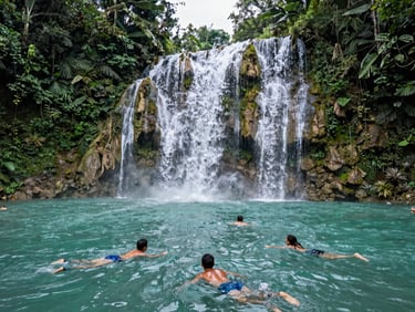 Wide shot of turquoise waterfalls in Huasteca Potosina, lush green jungle, young explorers swimming.