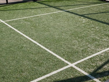 Overhead angle of a freshly lined padel court surface, no players, natural morning light revealing the texture and precision of the playing surface, clean and technical