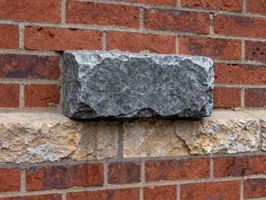 Gritty industrial photography of a hand-cast coping stone installed on a red brick wall, showing sharp drip grooves, natural overcast daylight, 35mm