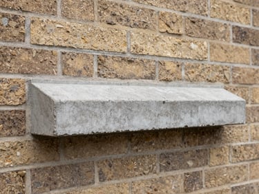 A hand-cast concrete window sill installed beneath a frame on a brick facade, sharp focus, 35mm