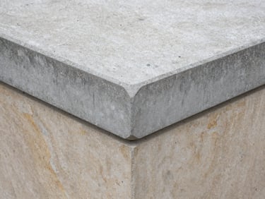Close-up of a hand-finished concrete pier cap, sharp geometric edges, natural overcast daylight, 35mm