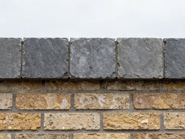 A run of slate-gray concrete coping stones installed on top of a brick wall, realistic weathering, 35mm
