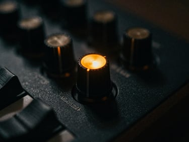 Moody low-key macro shot of a vintage analog synthesizer knob glowing in electric amber, deep shadows, cinematic film grain