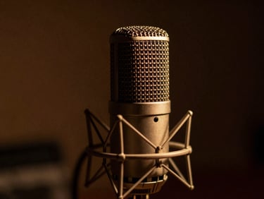 Close-up of an analog studio microphone, warm amber low-key lighting, rich dark background, 35mm