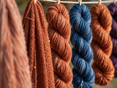 Macro shot of rich terracotta and indigo dyed yarn skeins drying in soft, warm morning sunlight, textured cotton threads, 35mm editorial photography.