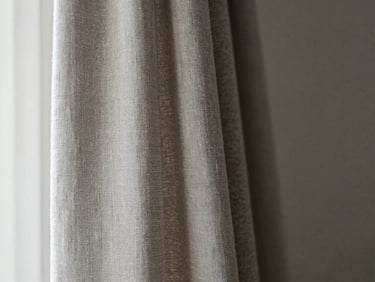 Close-up of heavy linen drapery folds hanging in a luxury interior, diffused side-light