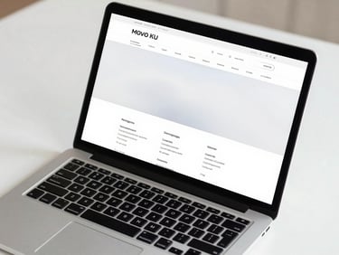 Close-up overhead of a laptop screen displaying a clean website layout, white desk, sharp studio lighting, minimal composition