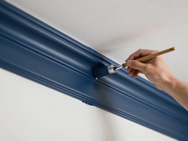 A master painter applying a flawless coat of navy paint to interior trim, showcasing a perfectly straight edge against a white wall.