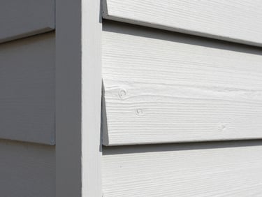 Close-up of clean, sharp paint lines on white cedar siding trim under bright daylight.