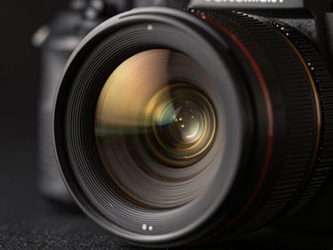 Macro close-up of a high-end camera lens reflecting golden studio lights, dark cinematic atmosphere, shallow depth of field.