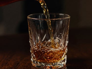 Moody cinematic close-up of amber liquid pouring into a heavy crystal glass, single light source, deep shadows