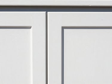 Close-up of freshly painted white cabinet doors with a perfect semi-gloss finish, clean workspace setup, bright natural daylight, 35mm.