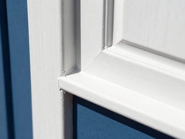 Macro detail of a pristine paint cut-in along a wooden door frame, perfectly taped edges, no dust, bright natural light, 35mm.