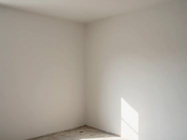 Freshly plastered and painted interior wall corner in a bare room, natural noon daylight, clean edge detail visible, documentary wide angle