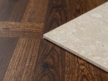 Straight-on macro shot of a clean material transition where a dark oak floor meets a light travertine stone tile with a perfect, razor-thin joint, soft natural light.