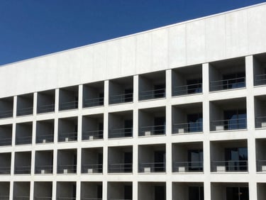 Plano arquitectónico detallado superpuesto en una estructura industrial moderna y terminada, luz diurna brillante, sombras de alto contraste, tonos azules y blancos.