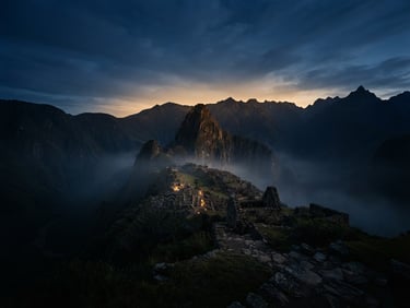 Wide panoramic shot of a subtle Andean mountain range at dawn, soft mist, ancient stone structures barely visible, warm golden light, low horizon.