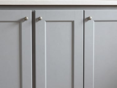 Close-up of freshly painted kitchen cabinet doors in soft gray, smooth factory-like finish, clean hardware, bright natural light, sharp focus, 35mm
