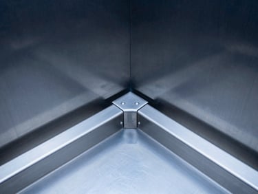 Macro technical shot of a brushed stainless steel elevator door mechanism, clean geometric alignment, sharp focus on mechanical tracks.