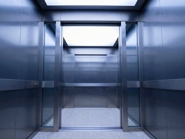 Symmetrical interior perspective of a premium glass and brushed steel elevator cabin, sharp architectural lighting, minimalist design.