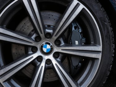 Moody macro shot of a grey BMW M Sport alloy wheel and brake caliper under cool overcast daylight, sharp details