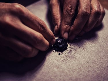 Close-up macro of hands working with raw charcoal on textured paper, dramatic chiaroscuro lighting, deep shadows