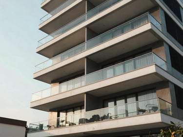 Luxury modern apartment building in Jhamsikhel, Lalitpur, featuring large glass balconies, clean architectural lines, bright afternoon sky.