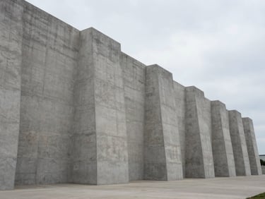 Wide-angle shot of a monolithic concrete facility, clean geometric lines, overcast daylight, pale sky