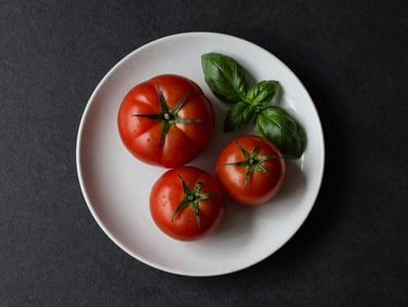 Minimalist Scandinavian food photography, top-down view of raw organic heirloom tomatoes and fresh basil on a clean matte ceramic plate, soft natural side-light, high-contrast shadows.