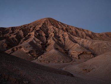 Low-angle shot of a wide desert mesa at twilight, dramatic rock formations, deep shadows, clean horizon.