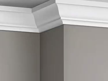 crown molding painted white installed in a room with grey paint on the walls.