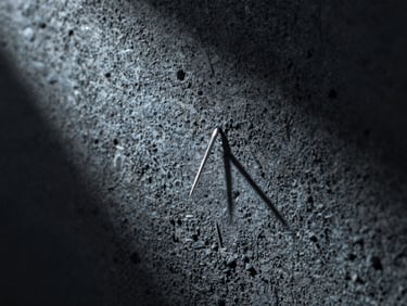 Macro close-up of a rough dark concrete wall texture with a single sharp needle of light cutting through darkness, cool silver and blue tones.