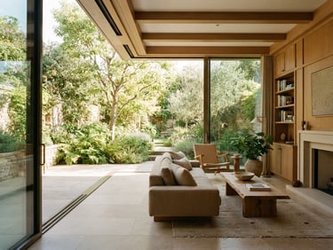 Warm architectural residential interior with a flush threshold leading to a sunlit garden, smooth oak details, soft sand-colored stone floor, bright natural daylight, 35mm.