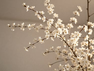 Close-up of an architectural floral installation with white delicate blossoms and branches, neutral background, soft diffused natural light