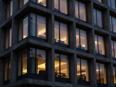 Architectural detail of a modern concrete and glass facade at dusk, warm interior light contrasting with deep obsidian shadows, cinematic 35mm