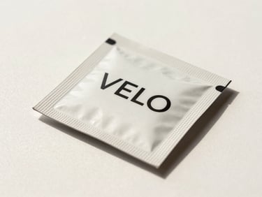 Studio flat of VELO nicotine pouch pack on a clean off-white surface, soft fill light, pack label detail sharp, subtle directional shadow to the lower right, warm-white background with minimal styling