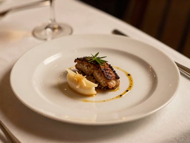 Close-up three-quarter angle of an elegantly plated wedding dinner course, warm golden light, white plate on ivory linen, delicate garnish visible